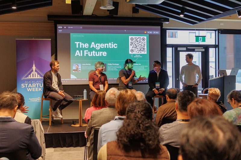 A seated audience watching the Agentic AI Future panel at NZVC Portfolio Day 2025, beside an Auckland Startup Week banner