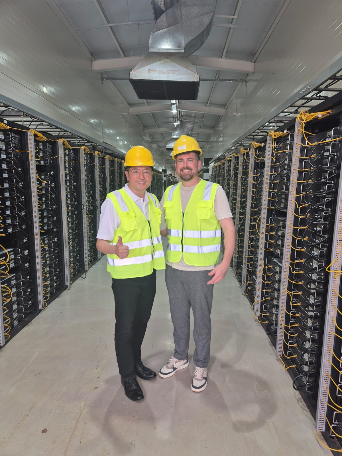 Two of the General Compute team standing between data centre racks